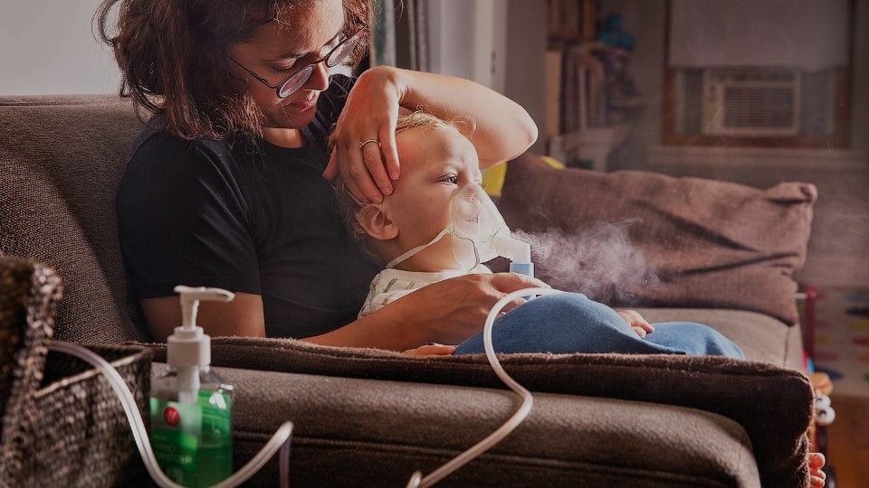 caregiver holding a baby using the nebuliser